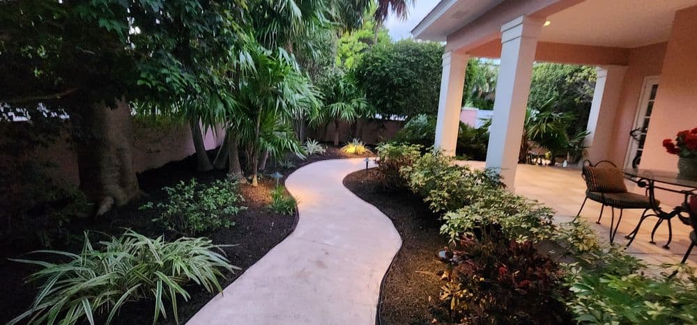 Serene garden pathway surrounded by lush greenery and outdoor seating area.